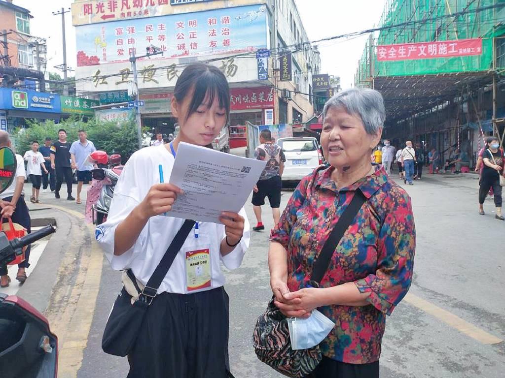 图为实践队员在湖北省十堰市的街道向老人们寻访调查购买商品的支付方式。