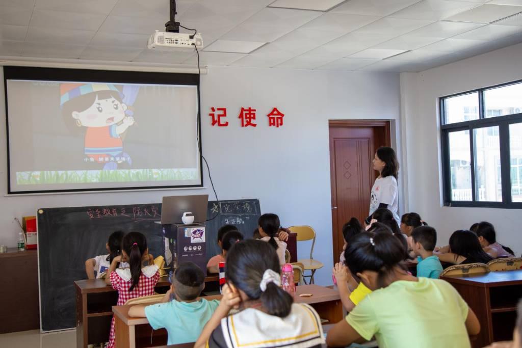 图为义教老师利用多媒体设备为同学们播放安全教育动画。