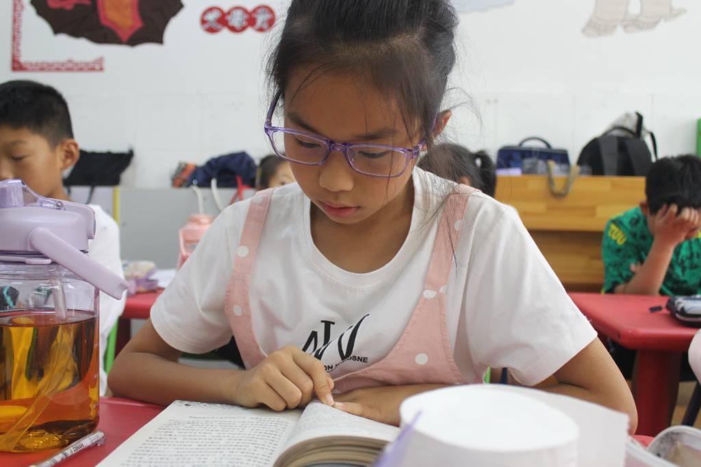 图为小朋友在阅读课上听完志愿者队书籍的讲解后认真阅读志愿者所介绍的书籍《云边有个小卖部》。中国青年网通讯员 景思溢 摄