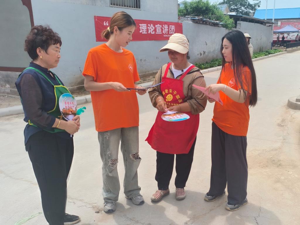 图为实践团成员在村庄中向村民介绍用电安全知识。 中国青年网通讯员 李静怡 摄