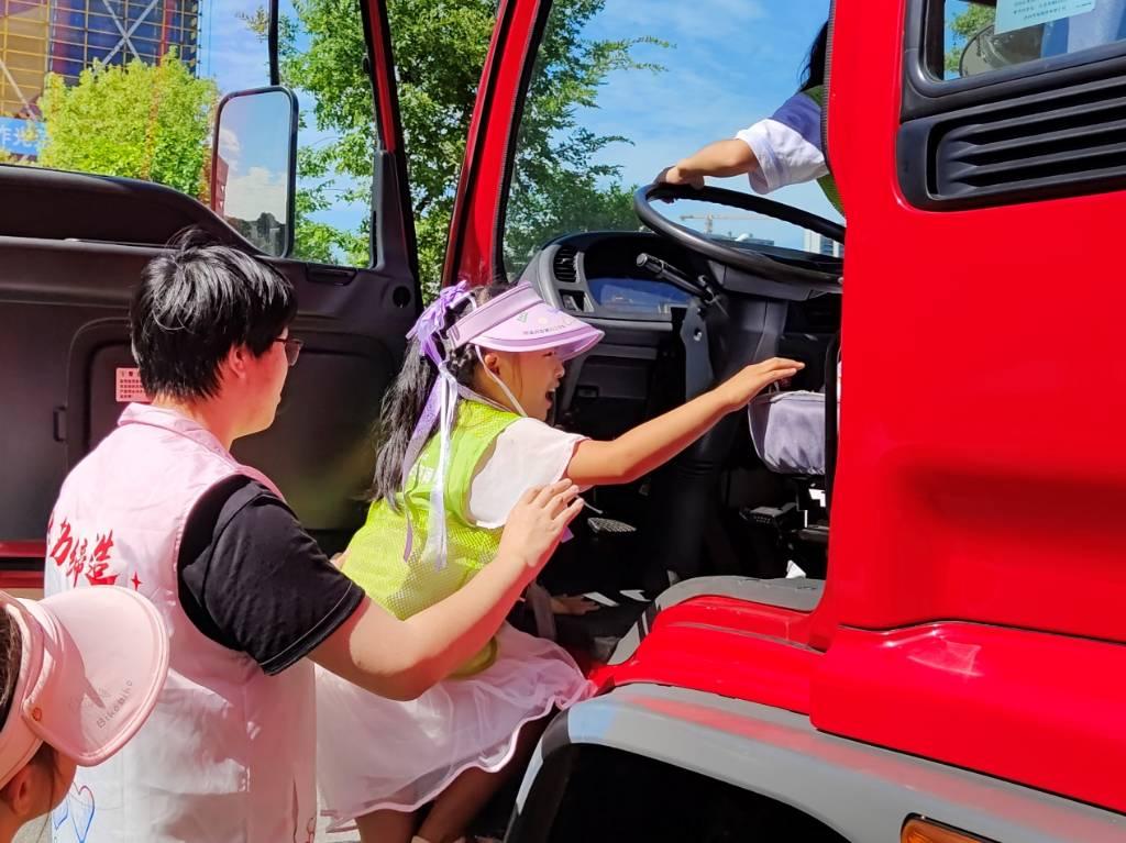图为消防员讲解完各种类型的消防车后，志愿者帮助小朋友上车体验的画面。中国大学生网报通讯员 赵梓茗 摄