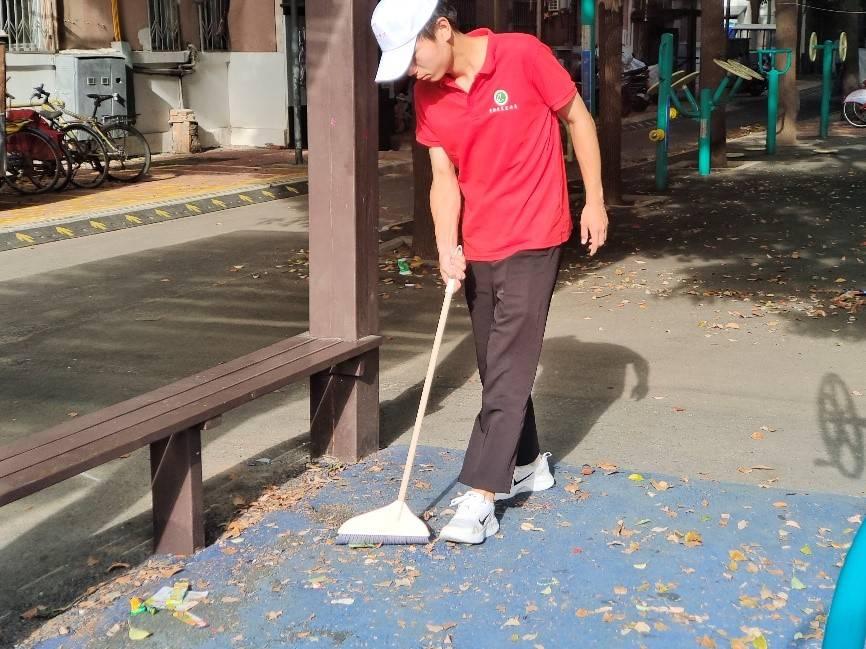 图为志愿者清扫社区健身区的落叶。 （刘欣 摄）