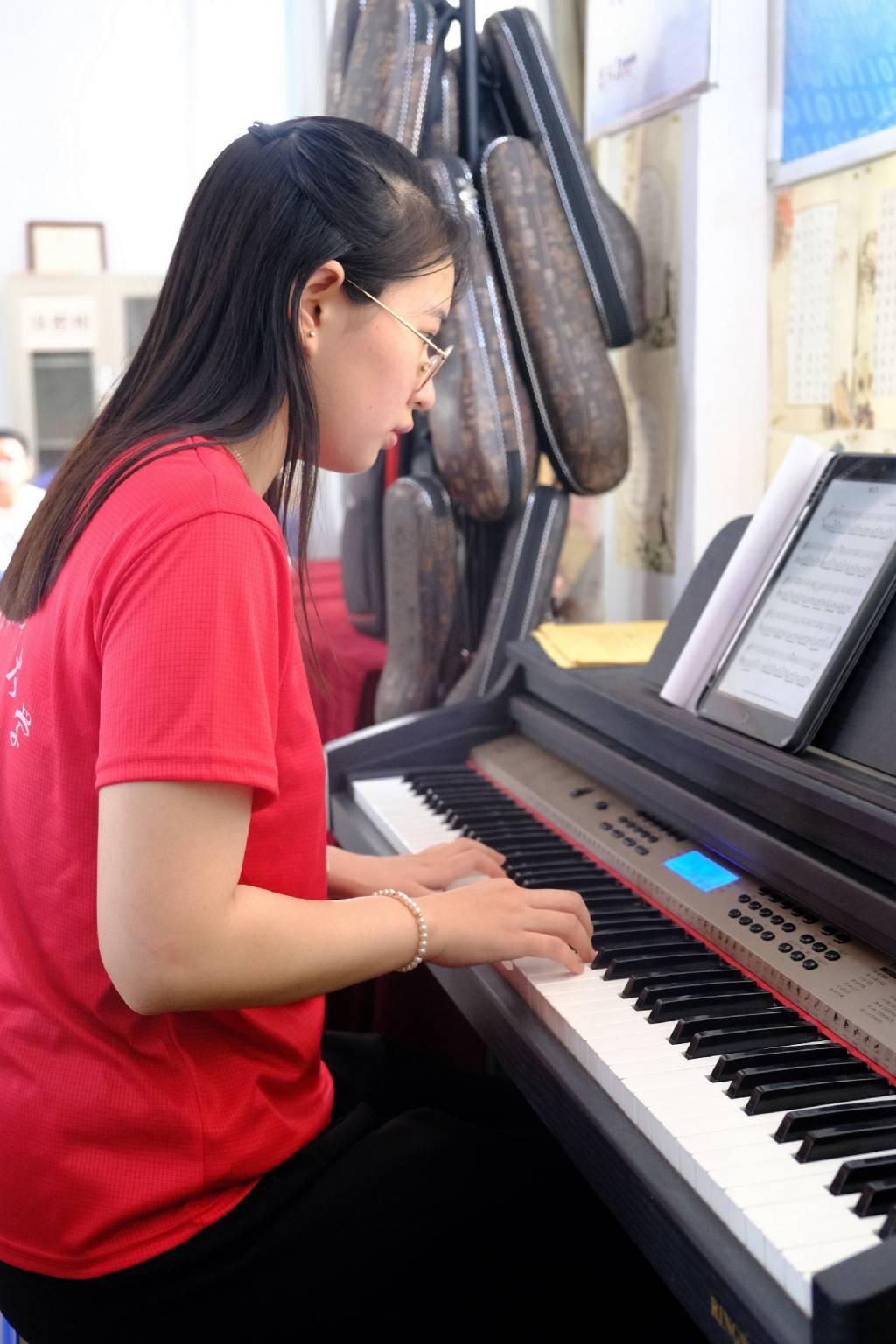 图为志愿者在重渠小学为学生弹电子琴伴奏，与学生们一起放声歌唱。