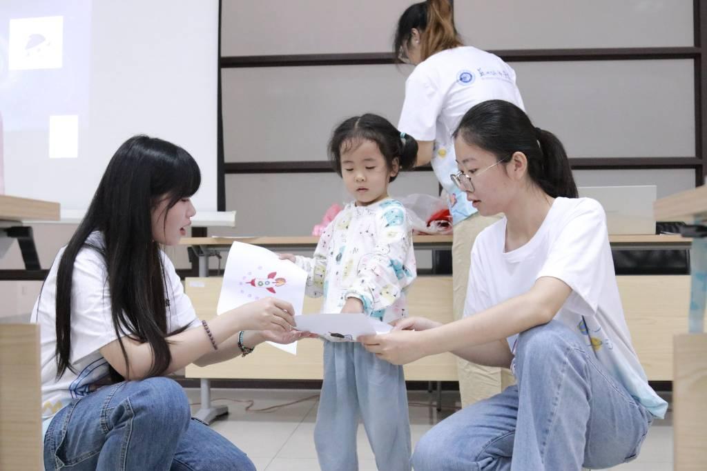 图为苏州城市学院志愿者辅助小朋友介绍自己的作品。