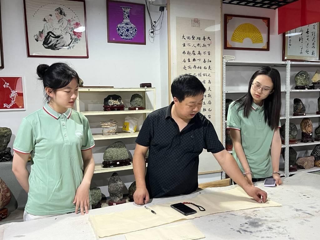 团队成员与当地书刻艺术家杨波讨论书刻作品设计方案。实践团成员杨舒羽供图。