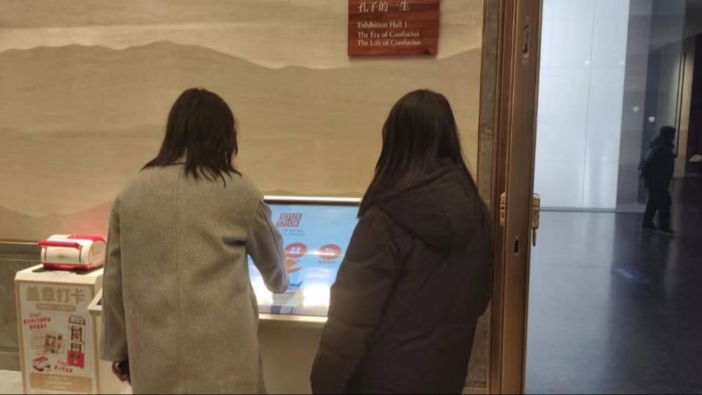 图为绘梦筑基实践队队员们用数字媒体查看孔子博物馆的参观事项。