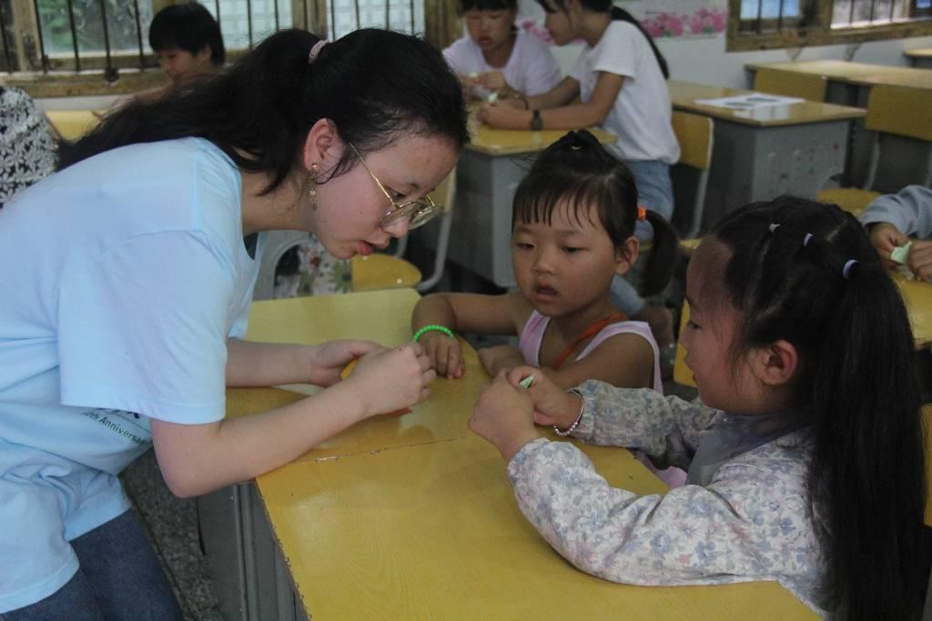 志愿者在台上讲解了折纸的步骤后，手把手教孩子们折“樱花”。近距离教学使志愿者与孩子们的关系更亲密了。