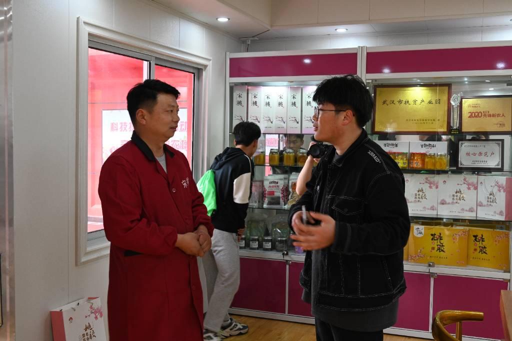 图为武汉美涛种植业专业合作社负责人张勤向队长邓醒介绍宋寨“桃”为核心的系列产品